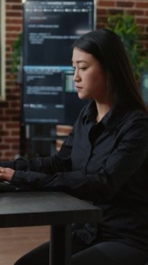 Vertical video System engineer focused on writing code sitting at desk in software development office while team of coders are developing cloud computing app. Programer concentrating on creating