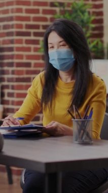 Vertical video: Business worker interviewing candidate at job application meeting during covid 19 pandemic. Asian applicant signing recruitment papers and contract, hr employee hiring woman in office.
