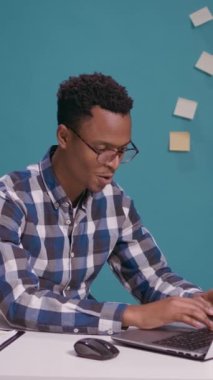 Dikey video: Diz üstü bilgisayarında dedikodu ve söylenti dinleyen Afrikalı Amerikalı bir adam, gizli bilgileri öğreniyor ve gizlice dinliyor. Gizli konuşmalara kulak misafiri olan genç..