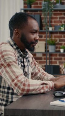 Vertical video Software developer typing programming code on computer keyboard turning head and smiling while innovating online cloud computing. Casual programer sitting at desk writing code feeling