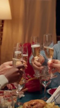 Dikey video: Şenlikli aile Noel 'i kutlamak için yemek odasında köpüklü şarap içerken evde toplandı. Kış tatilini Noel 'le kutlayan çeşitli insanlar var.