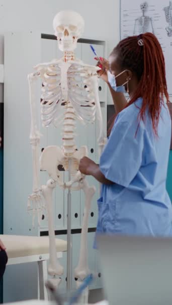 Vertical Video Medical Assistant Showing Human Skeleton Bones Old Patient — 비디오