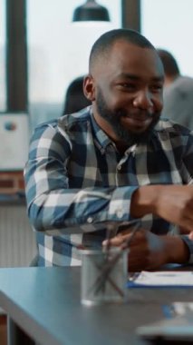 Dikey video: İK çalışanı iş başvurusu toplantısında iş bulma, başvuru adayıyla görüşme gibi konularda görüşmek için iş arayanı selamlıyor. Bir kadın, bir erkekle şirket işi hakkında konuşuyor..