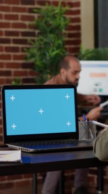 Vertical video: Office worker using laptop with greenscreen display at job, working with isolated blank template and mockup copyspace background on chroma key computer screen. Business manager.