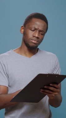 Dikey video: Mali analist pano belgeleri üzerine notlar alıyor, kağıtlara araştırma bilgileri yazıyor. Başarılı akıllı adam dosya ve kalem kullanarak program ve analiz, sermaye yaratıyor