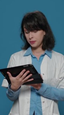 Dikey video: İnterneti taramak ve biyokimya keşfi bulmak için dijital tablet kullanan bir bilim adamı. İlaç tedavisi için cihazla çalışan kadın kimyager, mikrobiyoloji deneyi..