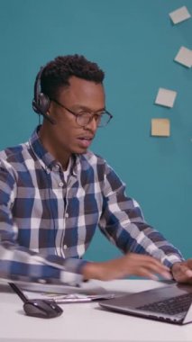 Dikey video: Arama merkezi operatörü, danışmada mikrofon ve dizüstü bilgisayarı olan bir kulaklık kullanarak müşteriyle yardım hattında tartışıyor. Tele pazarlama çalışanı müşteri destek servisine bağırıyor..