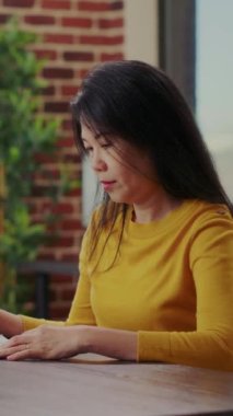 Vertical video: Portrait of person analyzing company paperwork for innovation, working with statistics documents to plan entrepreneurship. Woman using financial analysis to develop business career.