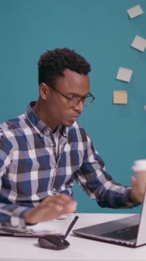 Dikey video: Afrikalı Amerikalı adam elleriyle şekil işareti yapıyor, kameranın önünde mola verme hareketi gösteriyor. Fazla mesaiye ara vermek için dizüstü bilgisayar ve reklam sembolü üzerinde çalışan kişi