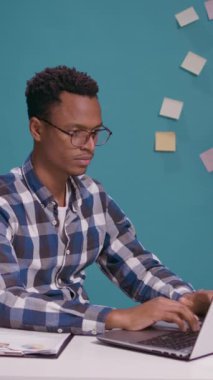 Dikey video: Kızgın çalışan laptopa bağırıyor ve iş hatası yüzünden hayal kırıklığına uğruyor. Sinirli ve öfkeli bir insan bilgisayara bağırıyor ve bağırıyor. Masa başında ağla ilgili sorun yaşıyor.