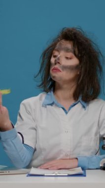 Dikey video: Petri kabındaki maddeye bakan, aptalca ifadeler yapan ve kamerada çılgınca davranan komik çılgın bilim adamı. Kirli suratlı ve patlamadan sonra dağınık saçlı aptal bir kimyager..