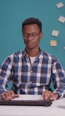 Vertical video: POV of office worker typing on computer and looking at camera, being focused on business career work. Financial analyst using laptop keyboard to plan leadership growth at desk.