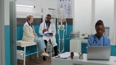 Doktor, kıdemli bir hastaya sağlık sigortası danışmanlığı yapıyor. Doktor muayenesi için muayenehanede buluşuyor. Kabinedeki sağlık uzmanı ile randevusu olan yaşlı bir kadın..
