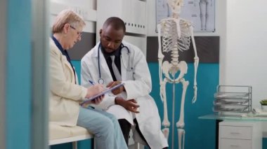 Hasta sağlık kontrolünde doktordan reçeteli ilaç ve tedavi desteği almak için check-up formu imzalıyor. Yaşlı kadın ve doktor sağlık danışmanlığında..