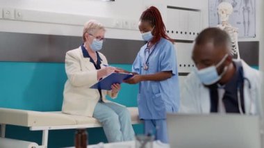 Kabinede salgın sırasında yaşlı bir kadına danışmanlık yapan tıbbi asistan. Hastalığı tedavi etmek için check-up yapıyor. Hemşire, kıdemli hastaya tanı koymada yardım ediyor, ilaç veriyor..
