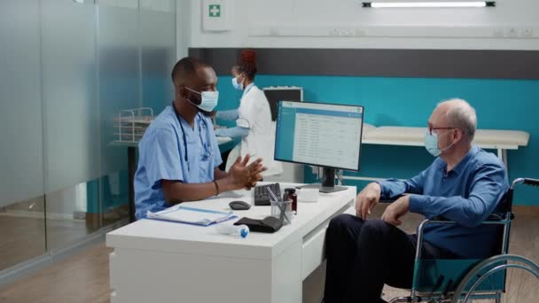Чоловіча Медсестра Проводить Консультації Літнім Чоловіком Інвалідному Візку Призначаючи Його — стокове відео