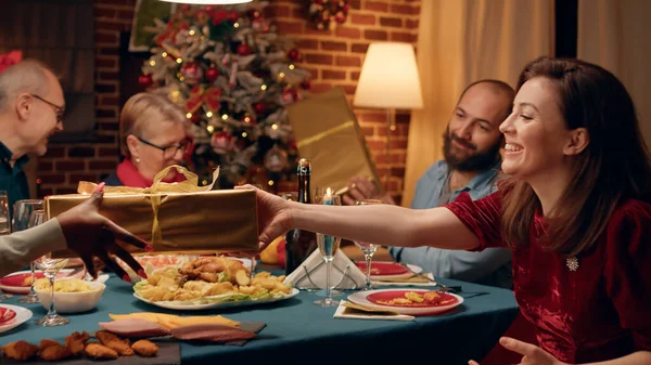 Festive Family Members Sitting Christmas Dinner Table While Exchanging Presents — Stock Fotó