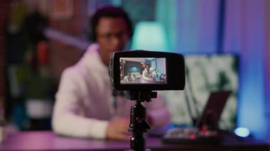 Selective focus on digital video camera screen recording african american content creator streaming live internet show from home. Influencer filming entertainment show for vlog social media post.