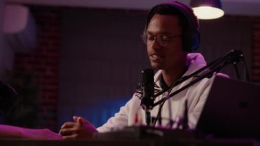 Afrika kökenli Amerikalı radyo sunucusu ev kayıt stüdyosuna şaşırmış gibi görünen nüfuzlu bir konukla konuşuyor. İçerik oluşturucusuyla podcast kaydetmek için profesyonel mikrofon kullanan ünlü podcaster.