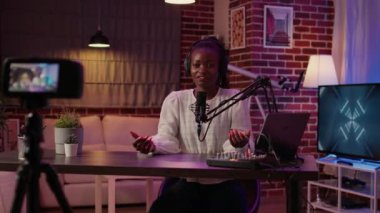 African american woman internet radio host recording live broadcast using digital video camera in home studio. Vlogger creating content while talking in professional microphone for social media page.