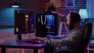 Caucasian man streaming first person shooter while explaining gameplay to subscribers in tournament. Gamer using pc gaming setup playing multiplayer online action game talking to team on headset.