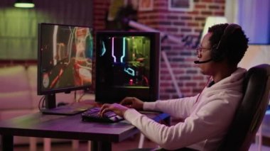 Handheld shot of gamer streaming multiplayer first person shooter angry after losing online tournament on gaming pc. African american man playing internet action game uspset after failing level.