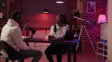 Closeup of african american online radio host recording podcast with male singer in late night interview in home studio. Portrait of woman talking with influencer for entertainment internet show.