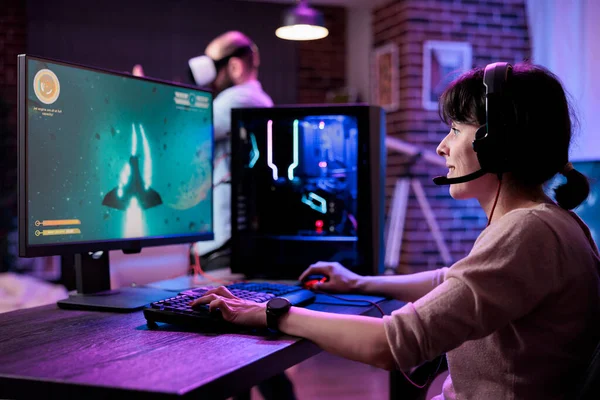 Modern gamer streaming online multiplayer video games play on computer, enjoying shooting gameplay tournament. Female streamer playing action rpg game competition on pc monitor.