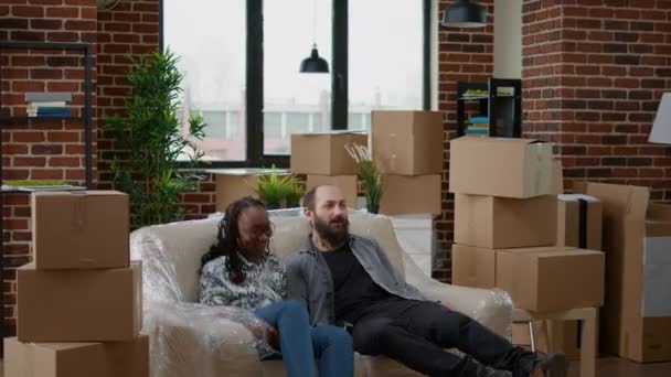 Multiethnic Couple Relaxing Sofa Unpacking Furniture Preparing Apartment Space Move — Wideo stockowe