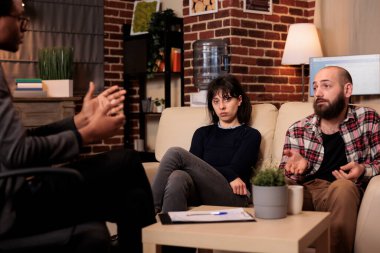 Endişeli eşin evlilik sorunlarını çözmek için koca ve psikologla terapi seansına katılmasının portresi. İlişki kavgasına yardım etmek için profesyonel danışmanlık ve danışmanlık almak.