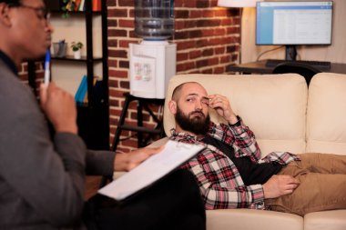 Terapide genç bir yetişkin kanepede uzanıp ofiste psikologla konuşuyor, ilişki problemlerini birlikte çözmek için anlatıyor. Danışmanlık uzmanıyla psikanaliz seansı.