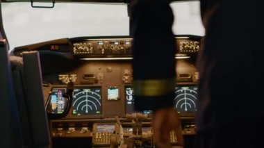 African american captain inserting destination coordinates to help pilot before takeoff, flying airplane with dashboard command. Using control panel buttons, windscreen compass and radar.