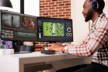Multimedya editörü evdeki birden fazla monitördeki video görüntülerini düzenlemek için yazılım kullanıyor, yapım uygulaması olan bir filmi bilgisayarda kurguluyor. Ortam içeriği oluşturmak için film montajı üzerinde çalışıyorum.