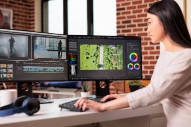 Asyalı grafik editörü prodüksiyon sonrası film içeriği yaratmak için profesyonel yazılımla video ve ses görüntüleri üzerinde çalışıyor. Multimedya filmi düzenlemek için film montajı kullanılıyor.