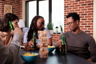 Farklı arkadaş grupları oturma odasında oturmuş, sosyete oyunlarıyla eğleniyorlar. Sıradan insanlar evlerinde oturup ahşap bloklarla eğleniyorlar.