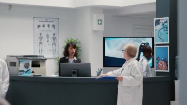 Kıdemli hekim bekleme odasının lobisinde sakat ve sağlık sorunu olan emekli bir hastayla konuşuyor. Felç olmuş tekerlekli sandalye kullanıcısıyla sağlık hizmetleri hakkında konuşmak. El kamerasıyla..
