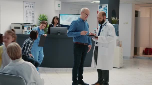 Lekarz Starszy Pacjent Patrzący Cyfrową Tabletkę Recepcji Szpitala Mówiący Diagnozie — Wideo stockowe
