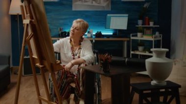Creative wheelchair user drawing authentic vase model with artistic tools and equipment, dealing with physical disability and having art and craft hobby. Paralyzed woman with health condition.