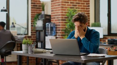 Tired overworked employee working in tension to plan project before deadline and create business presentation. Frustrated exhausted man being under stress and in despair, job failure.