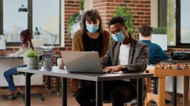 Diverse team of coworkers analyzing charts information on documents, using research data to plan business project. Creating online presentation with corporate report and successful plan.