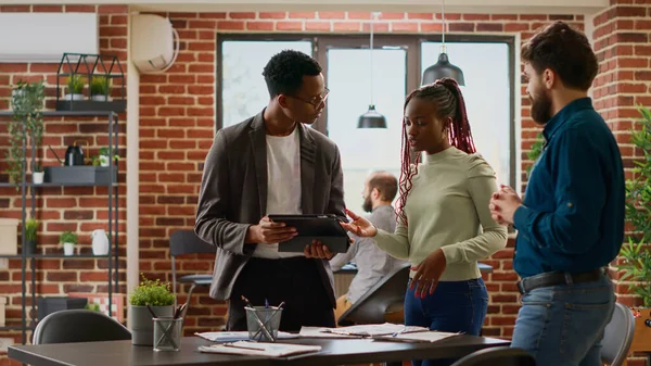 Diverse group of coworkers analyzing business charts in company office, planning startup presentation in boardroom meeting. People doing teamwork partnership with online data research.