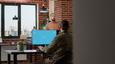 Company worker looking at greenscreen on computer and business charts, using chroma key display in office. Working with isolated copyspace template and blank mockup background.