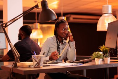Company employee answering landline phone call to talk about business research with project manager. Having remote conversation on office telephone line, chatting about email report.