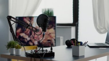 Empty broadcasting studio with professional audio equipment and no host. Radio podcast desk inside office workspace with laptop and microphone and nobody in it. Studio shoot