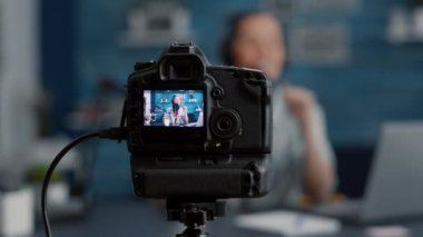Modern kamera kaydedicisi izleyicilerle konuşuyor. Popüler sosyal medya içeriği yaratıcısı stüdyo masasında otururken internet video paylaşım platformları için vlog kaydediyor. Kapat.