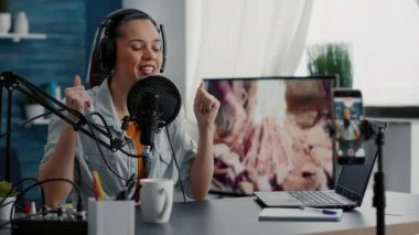 Joyful famous internet show host ending broadcast while sending air kisses to audience. Popular social media star saying goodbye to public while sitting at home studio desk.
