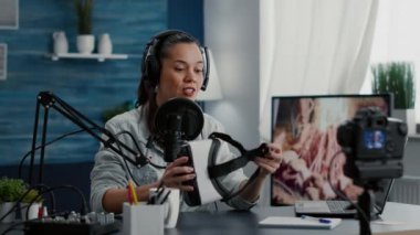 Content creator promoting modern VR headset while recording video. Famous social media influencer doing recommendation video while reviewing high tech weareable goggles to audience.