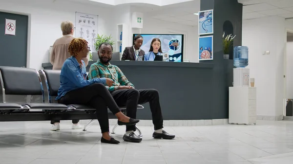 Afrykański Amerykanin Rozmawiający Chorobie Recepcji Szpitalnej Czekający Konsultację Specjalistą Pacjenci — Zdjęcie stockowe