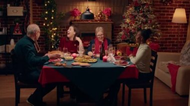 Funny husband surprises family on Christmas dinner when he appear disguised in Santa Claus with gifts. Goofy man enjoying winter holiday with close relatives while entering room looking like Santa.
