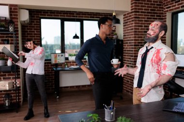 African american man talking to creepy monster in business office, having conversation with brain eating devil zombie. Undead sinister bloodthristy corpse chatting with person, eerie damaged devil.